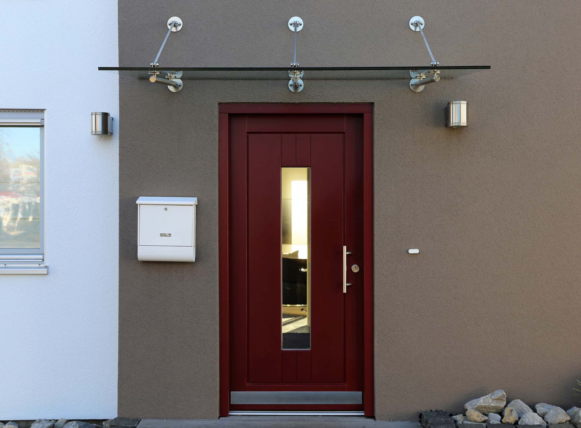 Moderne rote Eingangstür mit Glasüberdachung 